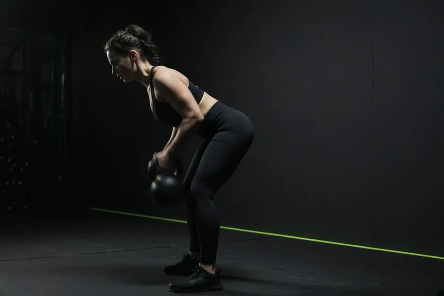 Una mujer entrenando con una pesa rusa
