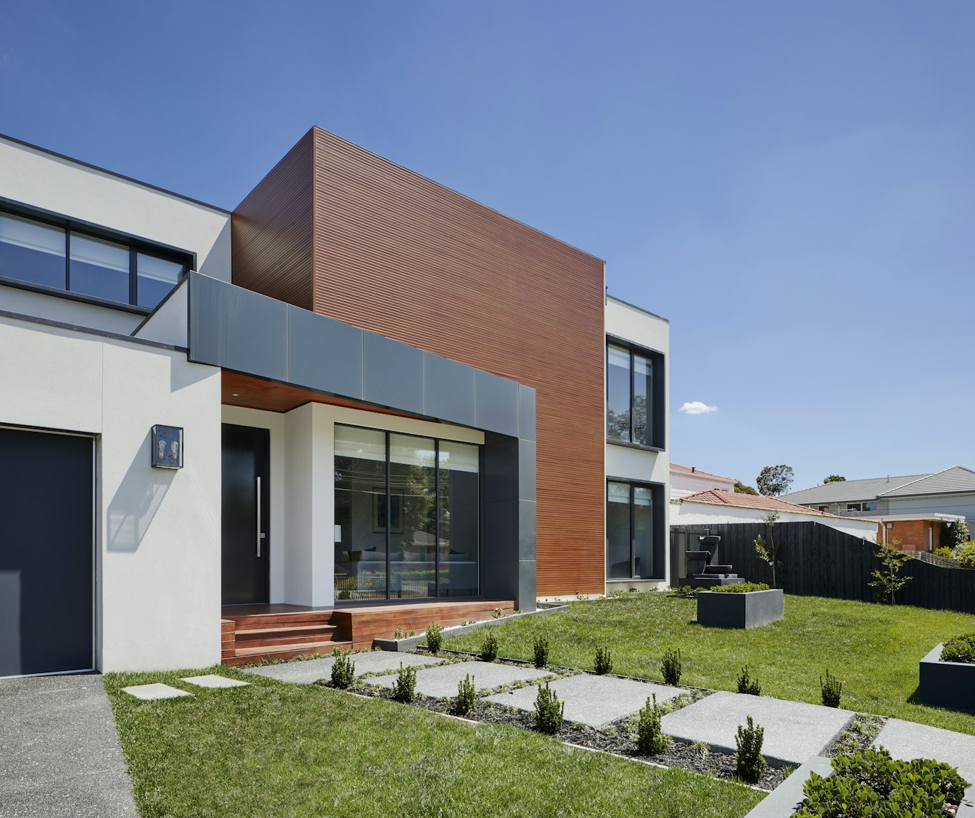 Frente del dúplex con jardín parquizado y detalles de madera